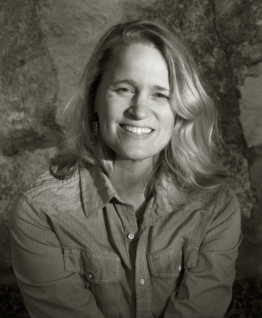 A black and white headshot of Suzanne Ohlmann wearing a buttoned up shirt with a collar.
