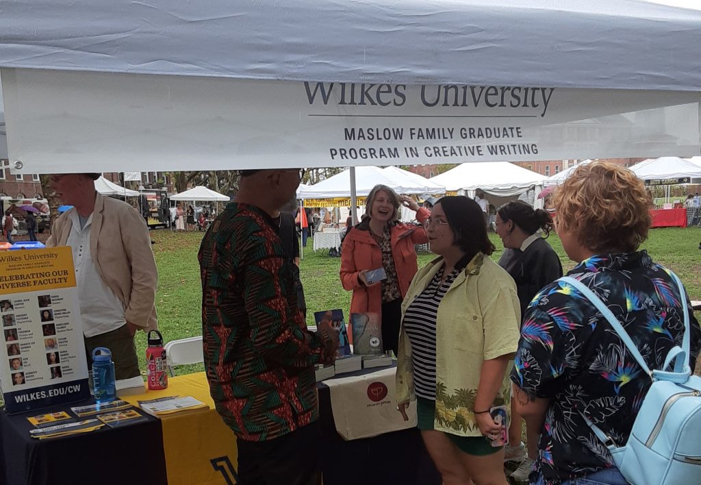 Image of the Wilkes Creative Writing booth at the New York City Poetry Festival in an outdoor park in Governers Island, NY.