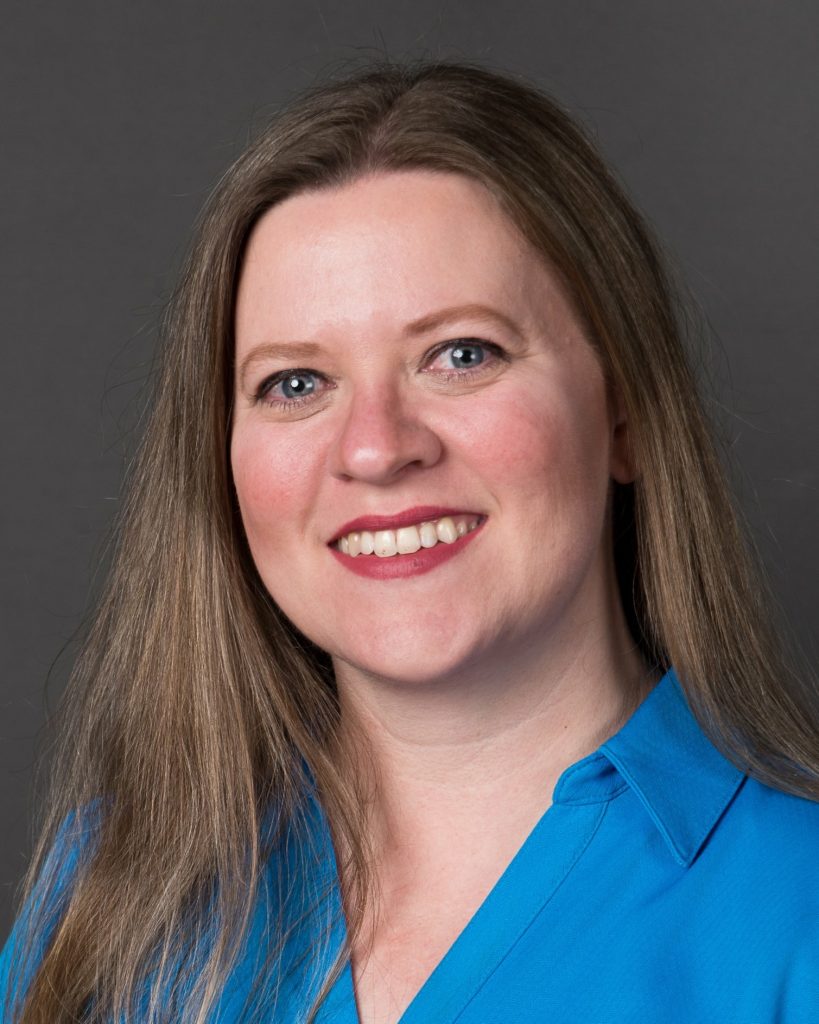 Headshot of Nicole Duncan smiling with red lipstick on and a blue shirt