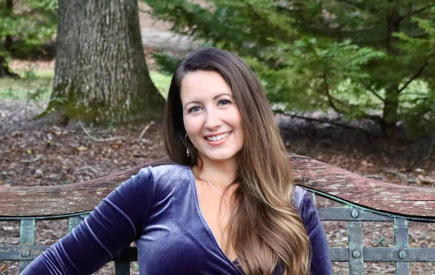 Photo of Amanda Rabaduex wearing a blue velvet shirt and smiling on a park bench