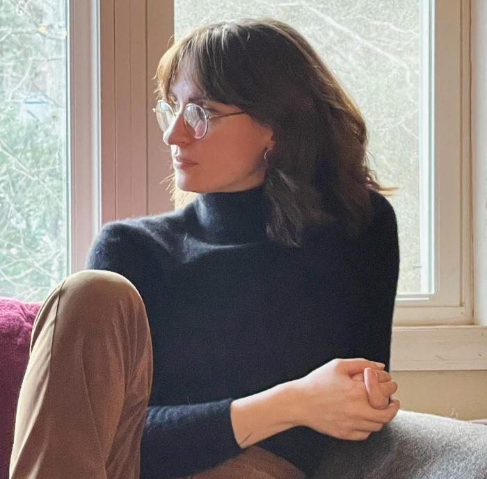 Photo of Jess Van Orden wearing a black turtleneck and glasses and looking off-camera